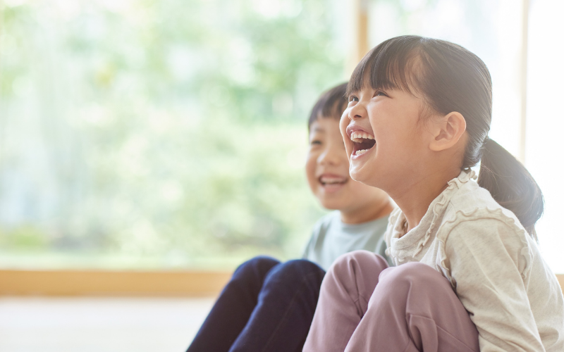 窓辺で楽しそうに笑う子どもたち